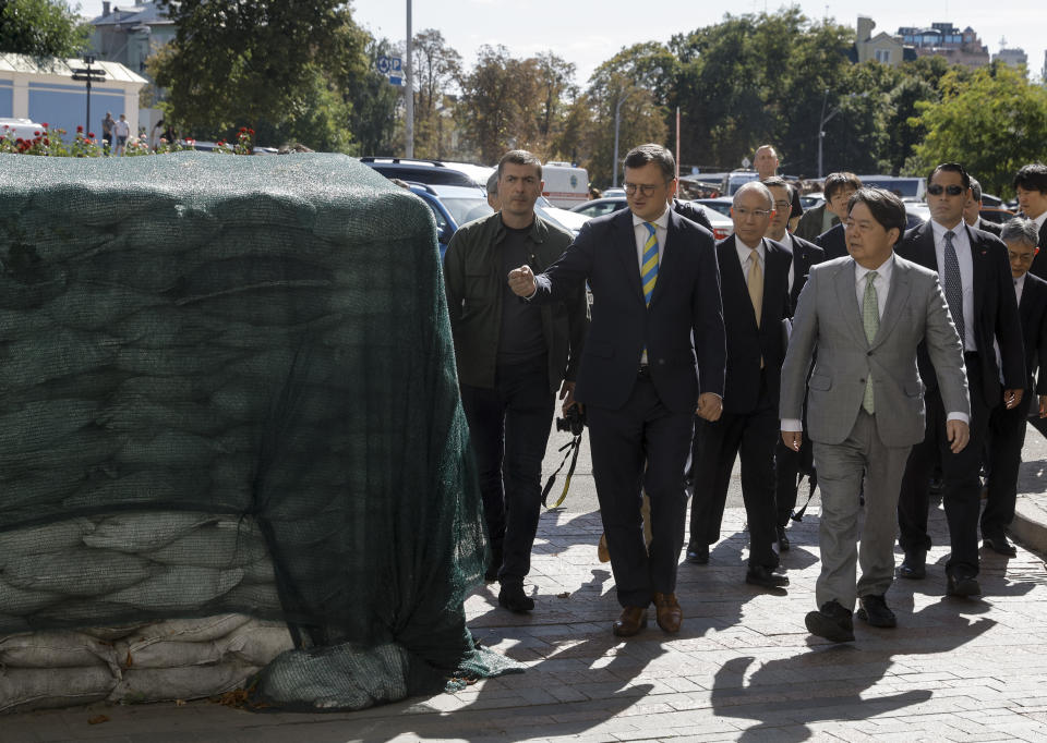 Ukraine's Foreign Minister Dmytro Kuleba, left, and his Japanese counterpart Yoshimasa Hayashi walk past bags with sand during their meeting in Kyiv, Ukraine, Saturday, Sept. 9, 2023. Japanese Foreign Minister Hayashi arrived in Ukraine's capital for an unannounced visit where he will meet with top Ukrainian officials. (Sergey Dolzhenko/pool via AP)