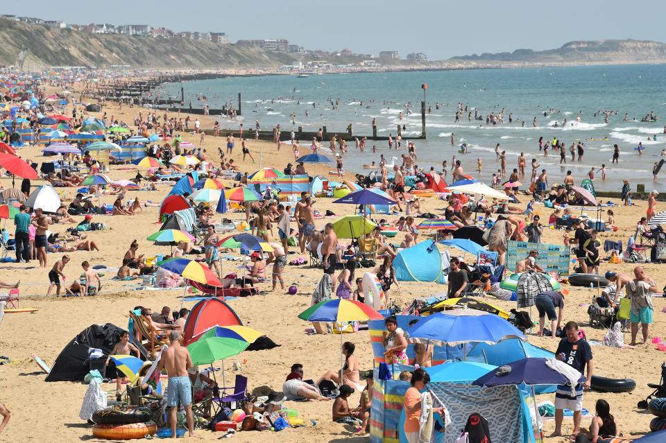 Beachgoers enjoy the sunshine as they sunbathe and play in the sea on Bournemouth beach in Bournemouth, southern England on July 31, 2020 as temperatures soar across the country. (Photo by Glyn KIRK / AFP) (Photo by GLYN KIRK/AFP via Getty Images)