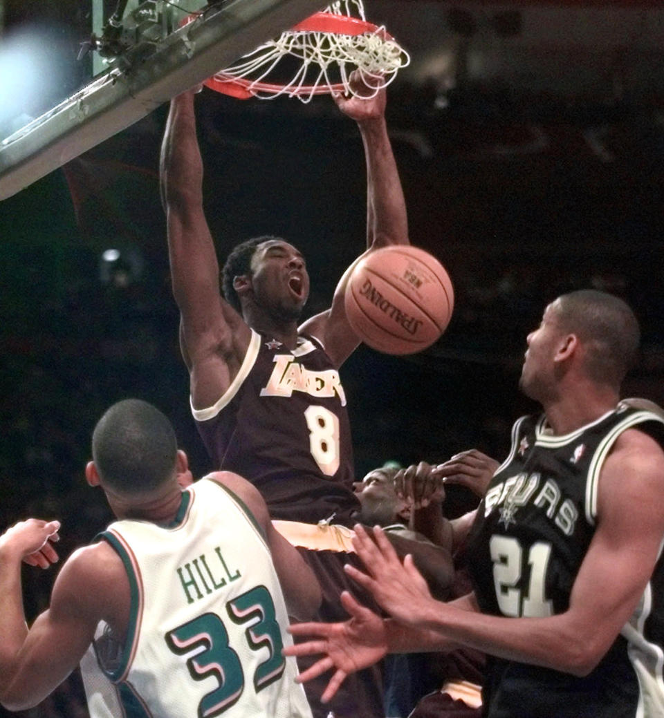 Los Angeles Lakers' Kobe Bryant, playing for the West All-Stars, reacts to his dunk over Detroit Pistons' Grant Hill and San Antonio Spurs' Tim Duncan, right, in the first half of the NBA All-Star game at New York's Madison Square Garden on Sunday, Feb. 8, 1998. (AP Photo/Mark Lennihan)