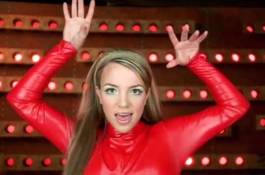 <p>The best way to dress up a red latex bodysuit? Frosted white eyeshadow and sleek straight hair. (Photo: YouTube)</p>