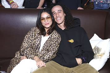 Vanessa Hudgens leans into Cole Tucker as they have their picture taken while sitting in a booth