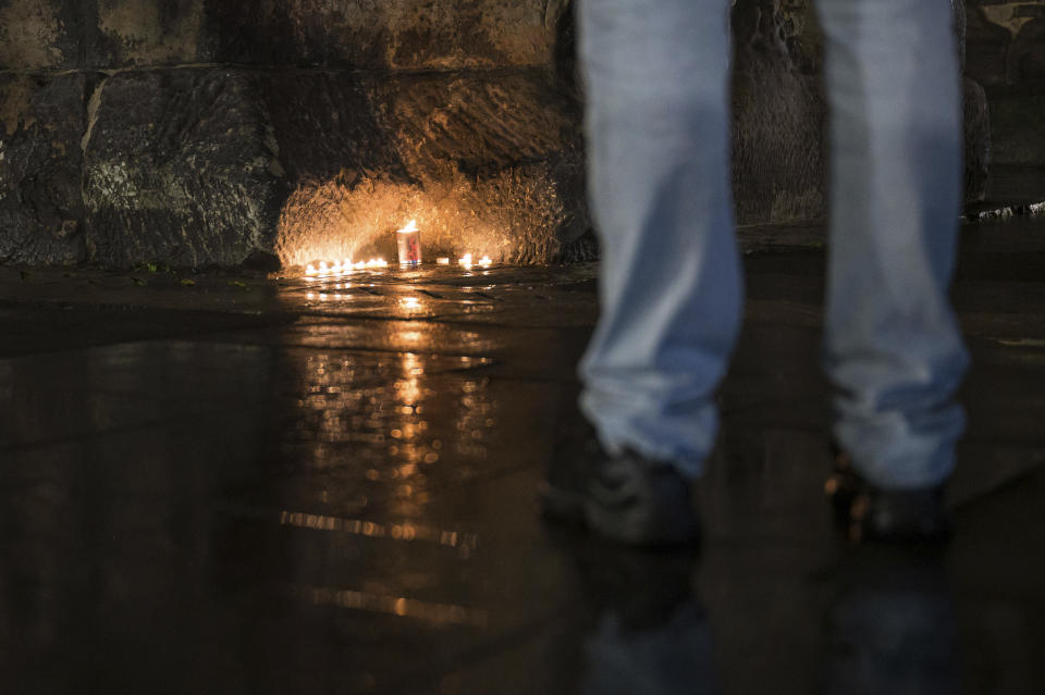 People lit candles at the historic Porta Nigra gate near the scene of an incident in Trier, Germany, Tuesday, Dec. 1, 2020. German police say people have been killed and several others injured in the southwestern German city of Trier when a car drove into a pedestrian zone. Trier police tweeted that the driver had been arrested and the vehicle impounded.( Oliver Dietze/dpa via AP)