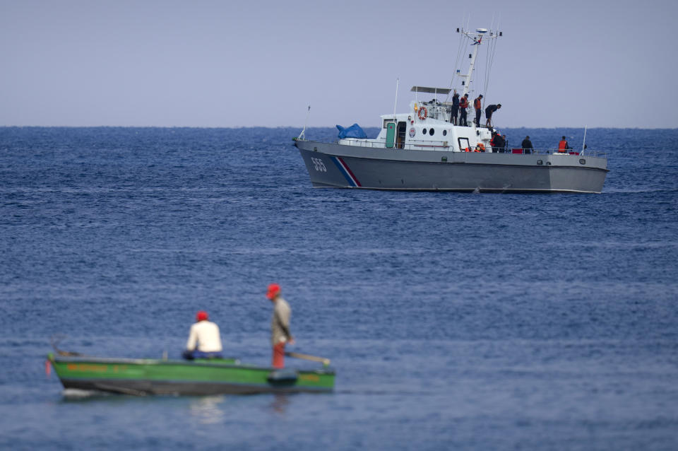 Fishermen watch a Cuban Coast Guards boat capture people traveling in a makeshift boat, blocked by the Coast Guard boat, near the Malecon seawall in Havana, Cuba, Monday, Dec. 12, 2022. (AP Photo/Ramon Espinosa)
