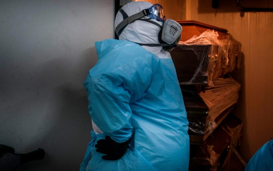 A funeral worker wearing a protection suit places a sealed casket of a Covid-19 victim in the refrigeration room containing other caskets of coronavirus victims at a funerary parlor in Amadora, in the outskirts of Lisbon, on January 29 - PATRICIA DE MELO MOREIRA/AFP 