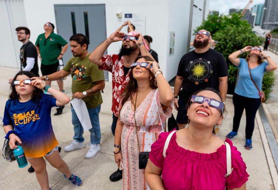 Ingrid Salamanca, bottom-right, watches a partial solar eclipse at the Frost Science Museum on Saturday, Oct. 14, 2023, in downtown Miami, Fla.