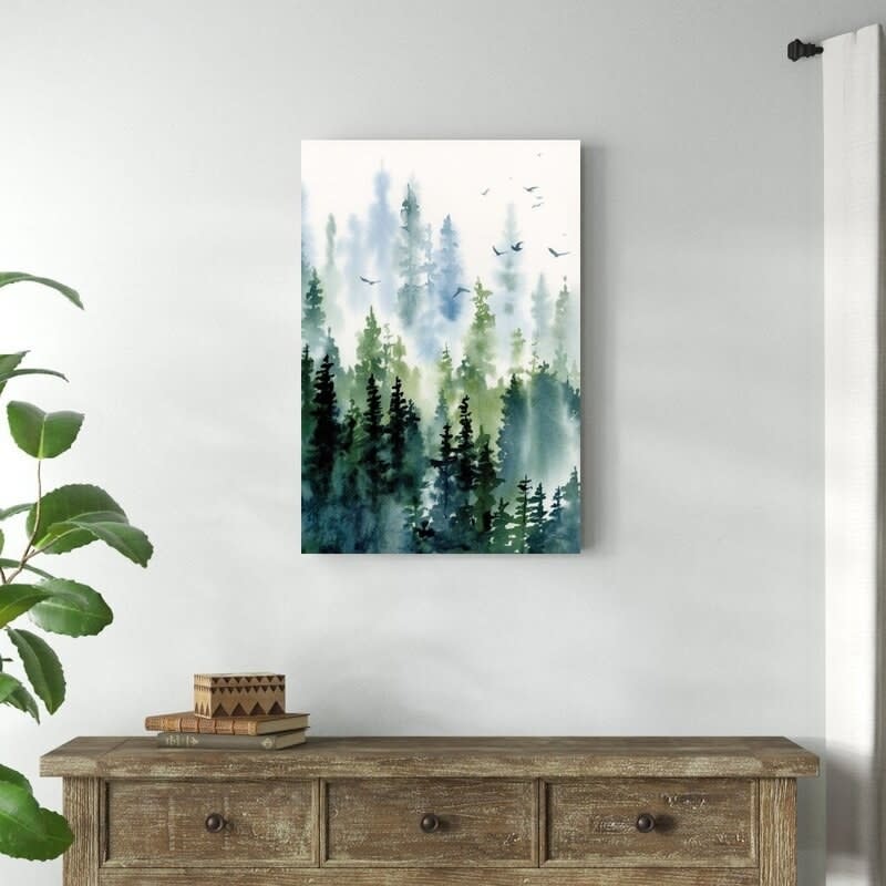 The print featuring trees and birds hanging above an accent table