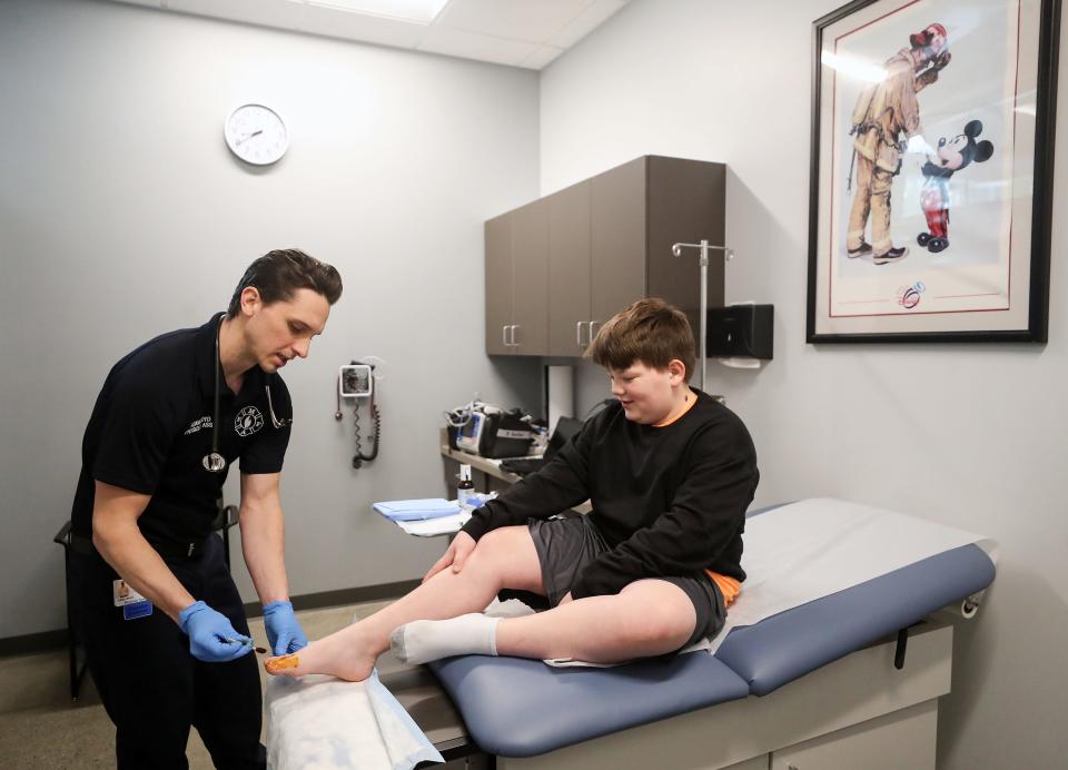 Certified Physician Associate Adam Boyd disinfects the toe of 10-year-old Blake Hicks, prior to a toenail removal in the exam room of North Mason Regional Fire Authority’s Station 21 in Belfair on April 20.