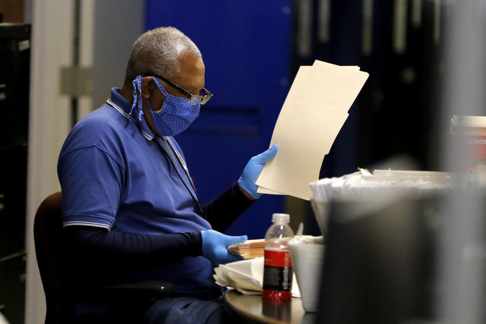 A Baltimore City Board of Elections worker sorts through folders at a canvasing warehouse ahead of the 7th Congressional District special election, Monday, April 27, 2020, in Baltimore. Democrat Kweisi Mfume and Republican Kimberly Klacik won special primaries for the Maryland congressional seat that was held by the late Elijah Cummings. Voters have been encouraged to mail in their ballots and only three in-person polling centers have been set up across the district in an effort to contain the spread of the new coronavirus. (AP Photo/Julio Cortez)