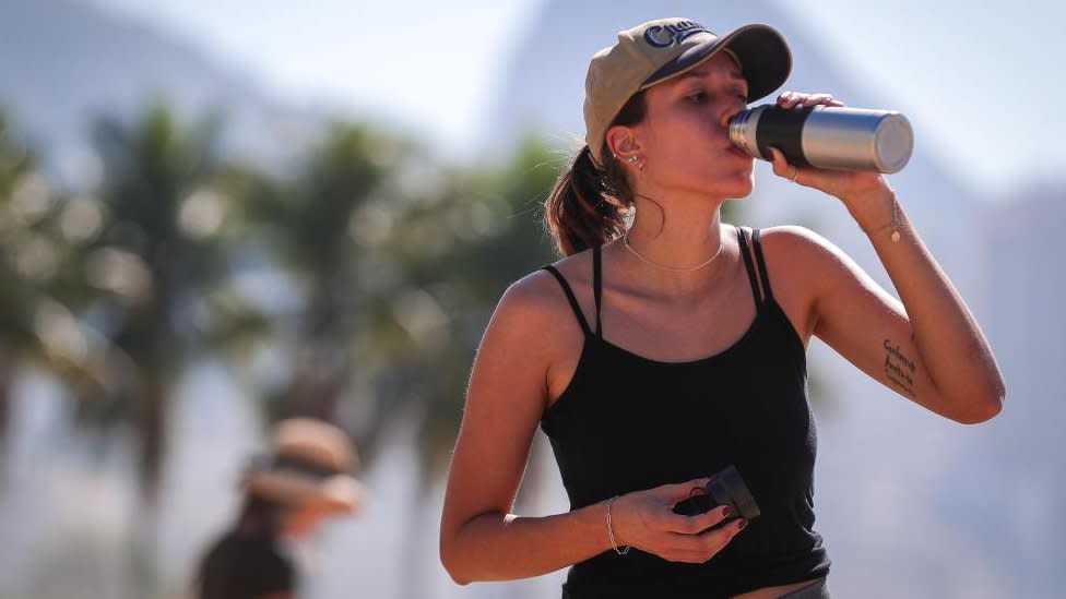 A woman drinks water on Copacabana Beach in Rio de Janeiro, Brazil, during a heatwave.