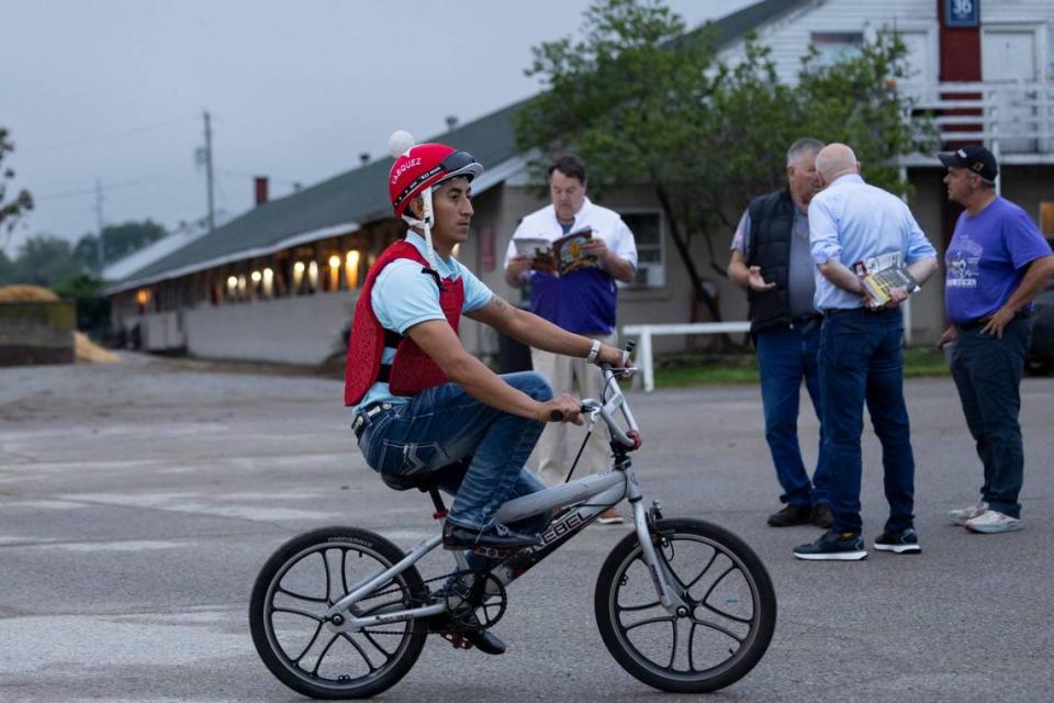 A jockey rides a bicycle back to the barns after morning workouts Saturday ahead of the 150th running of the Kentucky Derby at Churchill Downs.