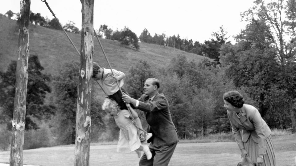 Prince Charles and Princess Anne being pushed on a swing by their father, the Duke of Edinburgh, with their mother Queen Elizabeth II looking on, in the grounds of Balmoral. 