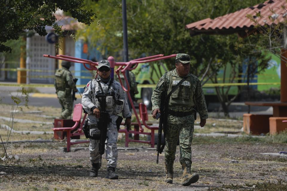 A member of the Mexican National Guard and a soldier leave a crime scene after clearing the area of onlookers, in a neighborhood of Celaya, Mexico, Thursday, Feb. 29, 2024. The National Guard doesn't arrest many suspects or investigate crimes. Like the military, it mainly follows orders and arrests criminals only if they are caught in the act. (AP Photo/Fernando Llano)