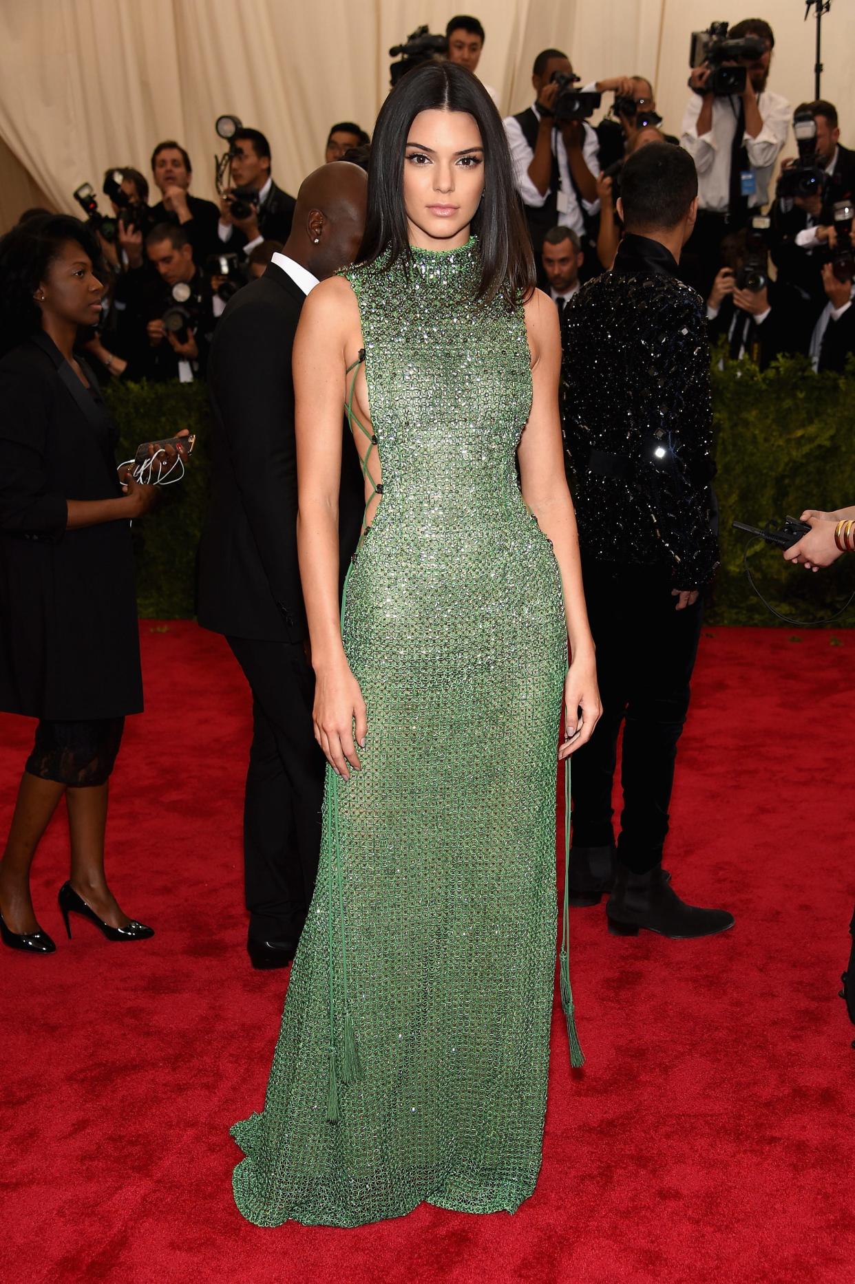 Kendall Jenner attends the 2015 Met Gala in a glittering green gown with exposed sides.