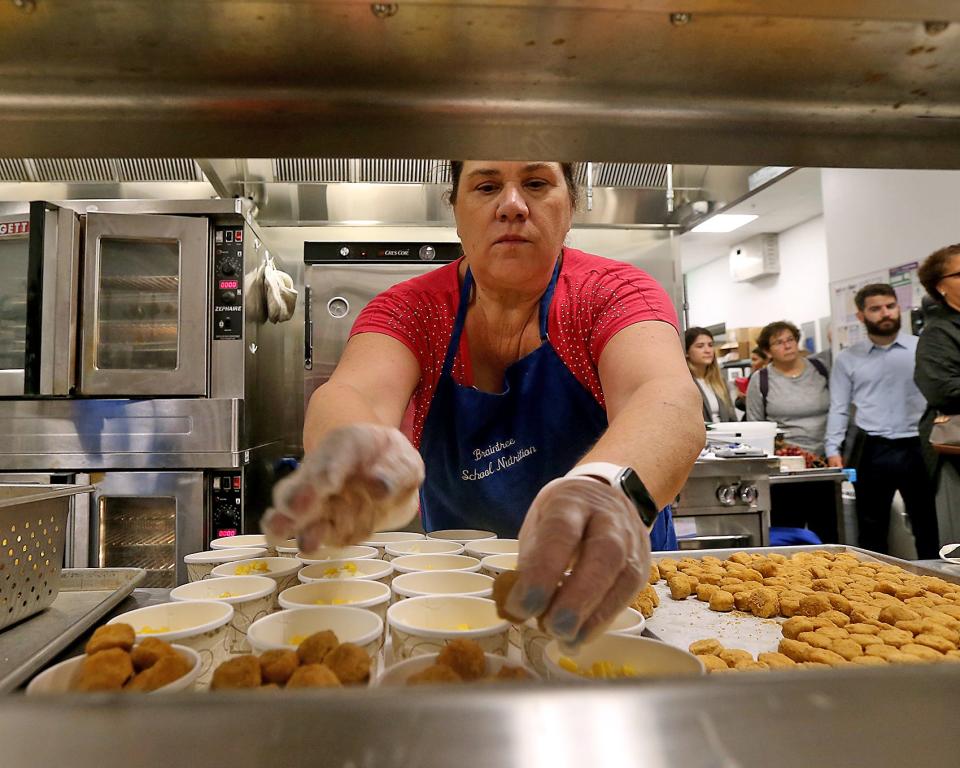 Dianne Sullivan drops chicken nuggets in a cup with corn while preparing lunch during a tour of East Middle School’s cafeteria in Braintree on Thursday.