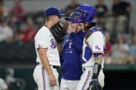 Texas Rangers starting pitcher Glenn Otto, left, pitching coach Doug Mathis, center, and catcher Jonah Heim confer on the mound during the first inning of the team's baseball game against the Oakland Athletics in Arlington, Texas, Monday, Aug. 15, 2022. (AP Photo/Tony Gutierrez)