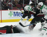 While covering up the puck, Arizona Coyotes goalie Scott Wedgewood (31) gets a face full of ice shavings from Dallas Stars' Joe Pavelski (16) and Coyotes' Kyle Capobianco (75) during the second period of an NHL hockey game Saturday, Nov. 27, 2021, in Glendale, Ariz. (AP Photo/Darryl Webb)