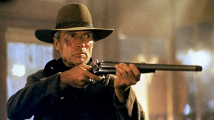 Clint Eastwood as William Munny aiming his rifle at someone off-camera in Unforgiven.