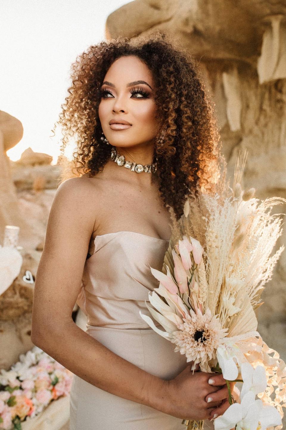 A bride poses in a desert and holds a bouquet.