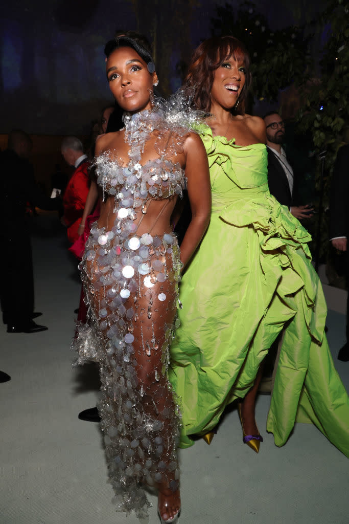 Two women at an event, one in a sheer, embellished gown and the other in a green dress with a ruffled skirt