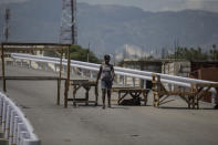 A woman walks past a barricade set up by gang members in Croix-des-Missions, north of Port-au-Prince, Haiti, Thursday, April 28, 2022. Gangs have forced schools, businesses and hospitals to close as they raid new neighborhoods, seize control of the main roads connecting the capital to the rest of the country and kidnap victims daily. (AP Photo/Odelyn Joseph)