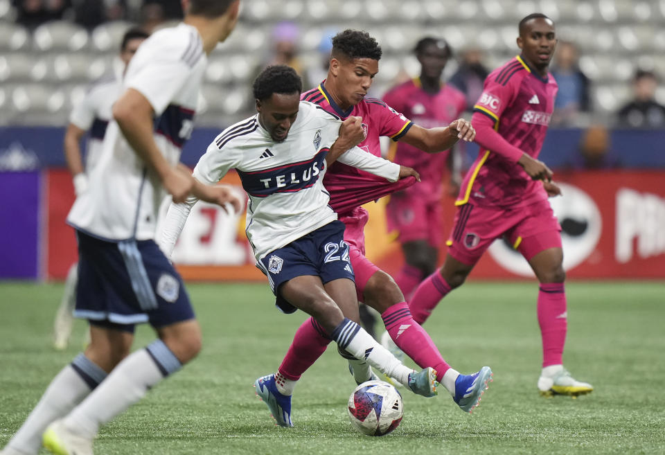 Vancouver Whitecaps' Ali Ahmed (22) grabs the jersey of St. Louis City's Nicholas Gioacchini's during the first half of an MLS soccer match Wednesday, Oct. 4, 2023, in Vancouver, British Columbia. (Darryl Dyck/The Canadian Press via AP)