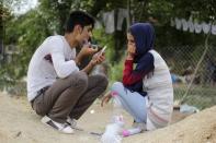 Sevar Ali (L), a migrant from Kurdistan region in northern Iraq, shaves next to his wife Vian Xhoshe, near a camp in the town of Presevo, Serbia, August 26, 2015. REUTERS/Agron Beqiri