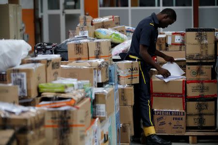 A security guard checks through documents on a cardboard box at a warehouse for online store, Jumia in Ikeja district, in Nigeria's commercial capital Lagos June 10, 2016.REUTERS/Akintunde Akinleye