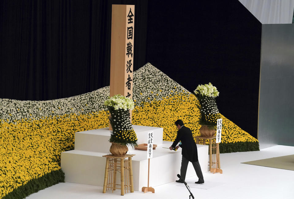 Japanese Prime Minister Shinzo Abe offers a flower for the war dead in front of the main altar decorated with huge bank of chrysanthemums Wednesday, Aug. 15, 2018, in Tokyo. Japan marked Wednesday the 73rd anniversary of the end of World War II. (AP Photo/Eugene Hoshiko)