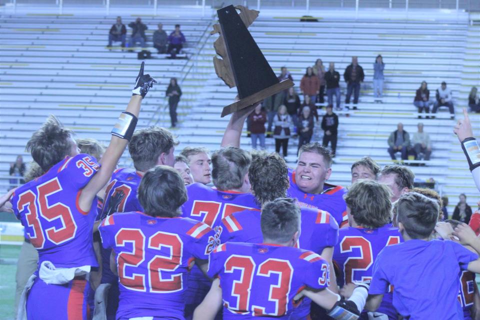 The Lenawee Christian football team celebrates with the trophy after beating Marion in a MHSAA 8-Player Division 2 state championship contest at the Superior Dome in Marquette on Saturday.