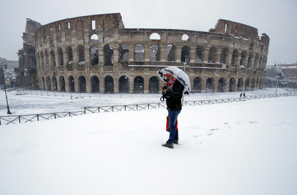 Un hombre de pie ante el antiguo Coliseo cubierto por la nieve en Roma, el lunes 26 de febrero de 2018. (AP Foto/Alessandra Tarantino)