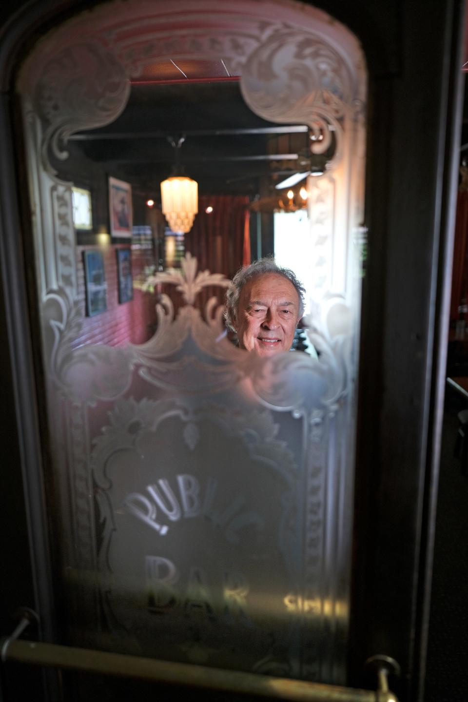 Jamil's Steakhouse owner Greg Gawey, stands behind one of his favorite items in the restaurant — glass doors originally from a bar in Purcell purchased at auction in the '70s.