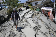 A man walks on a heavily damaged street due to the earthquake in Balaroa neighborhood in Palu, Central Sulawesi, Indonesia Indonesia, Tuesday, Oct. 2, 2018. Desperation was visible everywhere Tuesday among victims receiving little aid in areas heavily damaged by a massive earthquake and tsunami, four days after the disaster devastated parts of Indonesia's central Sulawesi island. (AP Photo/Dita Alangkara)