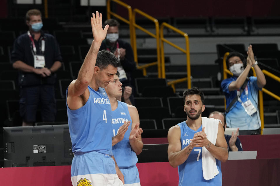 Argentina's Luis Scola (4) acknowledges an emotional standing ovation from his team, Australia players, and others in attendance when he was pulled from the game in the final moments of a men's basketball quarterfinal round game at the 2020 Summer Olympics, Tuesday, Aug. 3, 2021, in Saitama, Japan. (AP Photo/Eric Gay)