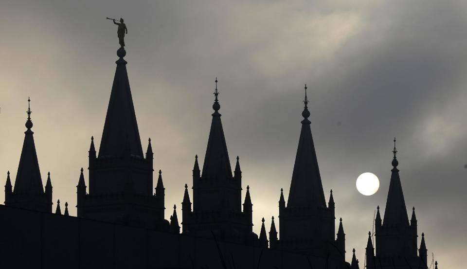 FILE - In this Feb. 6, 2013, file photo, the angel Moroni statue, silhouetted against a cloud-covered sky, sits atop the Salt Lake Temple in Temple Square in Salt Lake City. A newly-posted article, part of a series of recent online articles posted on the website of The Church of Jesus Christ of Latter-day Saints, affirms the faith's belief that humans can become like God in eternity, but explains that the "cartoonish image of people receiving their own planets" is not how the religion envisions it. (AP Photo/Rick Bowmer, File)