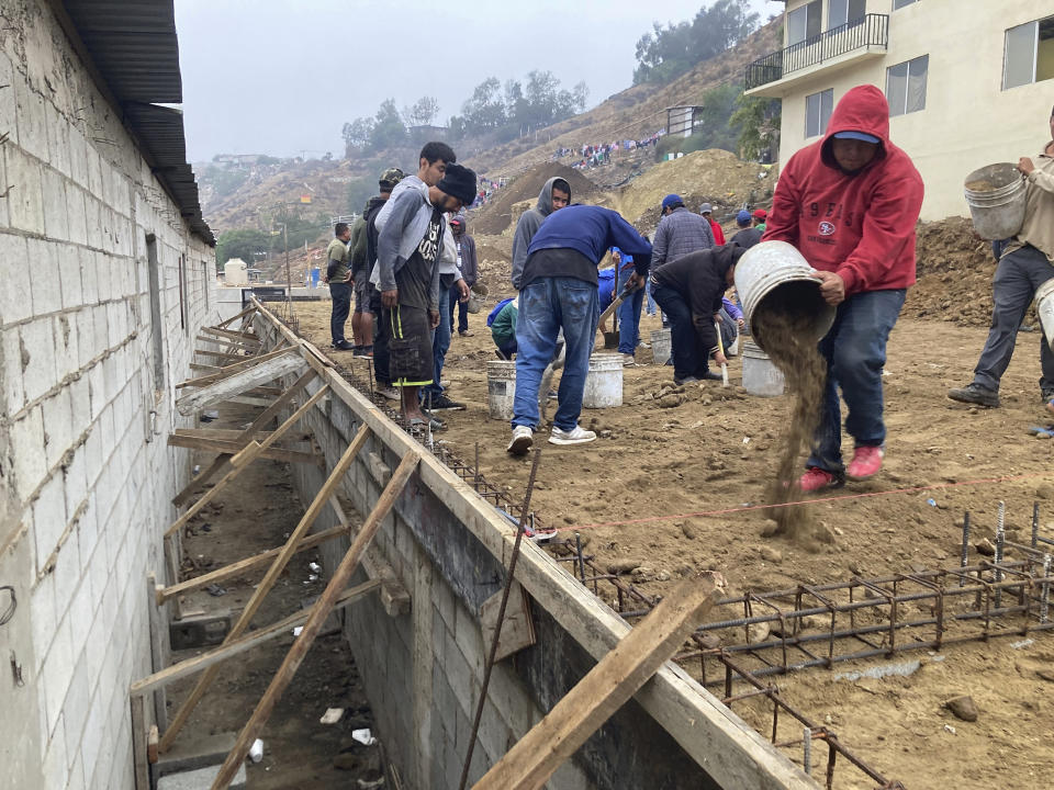 Voluntarios migrantes construyen un campo de fútbol en el Templo Embajadores de Jesús, el mayor albergue de la ciudad fronteriza mexicana de Tijuana, el 13 de octubre de 2022. El nuevo plan de EEUU que amplía las restricciones de asilo a los venezolanos supone un reto añadido para la ya desbordada red de albergues en México, que apenas puede hacer frente a la creciente llegada de extranjeros. Washington aceptará hasta 24.000 migrantes venezolanos que cumplan una serie de requisitos y devolverá a México a quienes entren de forma ilegal. (AP Foto/Elliot Spagat)