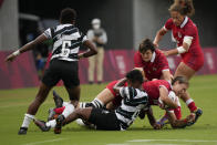 Canada's Kaili Lukan, carrying the ball, is tackled by Fiji's Viniana Riwai, as Canada's Britt Benn tries to assist, in their women's rugby sevens match at the 2020 Summer Olympics, Thursday, July 29, 2021 in Tokyo, Japan. (AP Photo/Shuji Kajiyama)