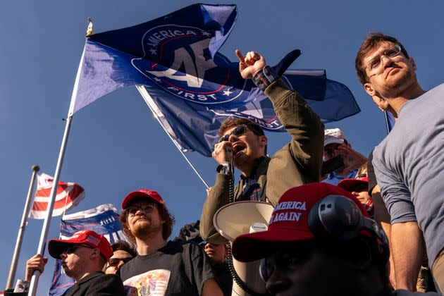 Nick Fuentes right-wing podcaster, center, speaks in front of flags that say, 