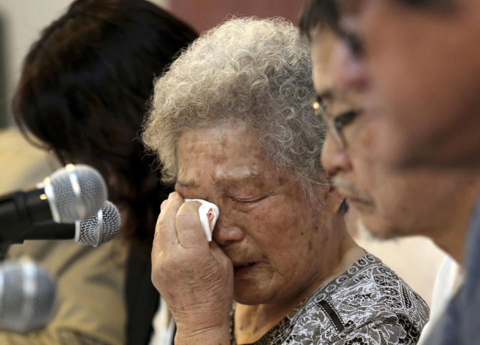 In this Aug. 14, 2019, photo, Kim Jeong-ju, center, an 88-year-old who is seeking compensation for her forced labor at a Japanese munitions factory in 1945, weeps during a press conference in Seoul, South Korea. “I lived like a slave there, but (Prime Minister) Abe is acting like he doesn’t know,” said Kim, during a news conference in Seoul. (AP Photo/Ahn Young-joon)