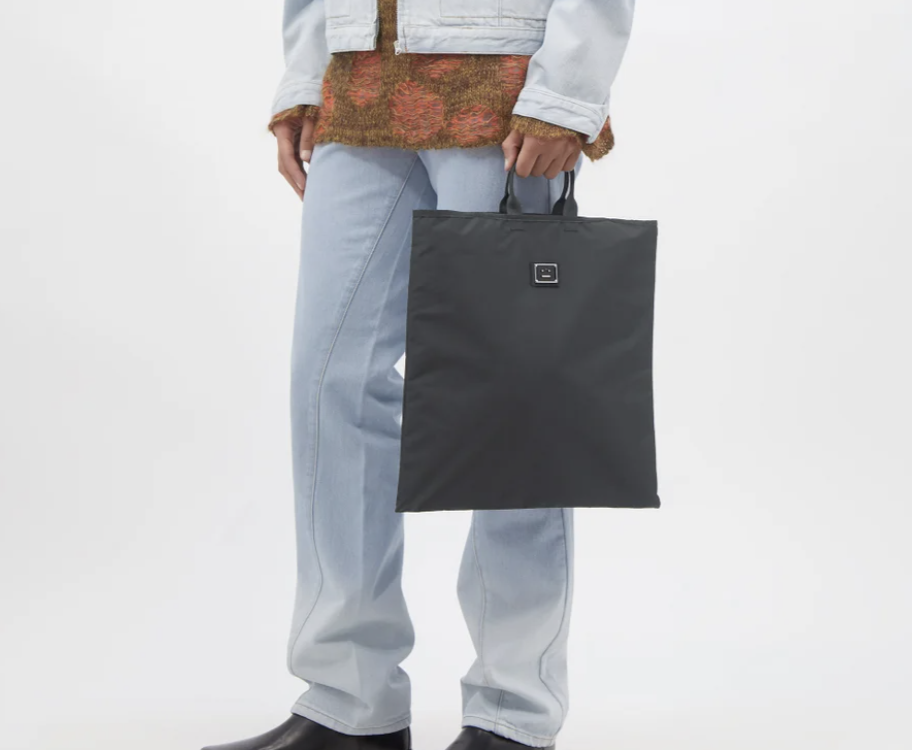 A model carrying Acne Studios Awen Face-patch shell tote bag.