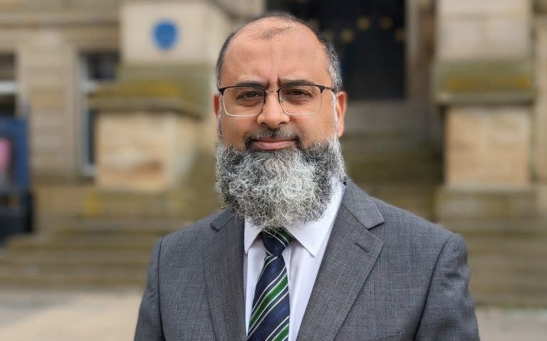 Mr Mohamed poses for a photograph outside a public building, wearing a suit and tie