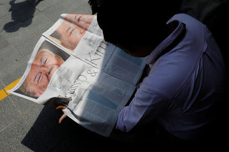 A journalist reads a local newspaper showing an article on the summit between U.S. President Donald Trump and North Korean leader Kim Jong Un near St. Regis hotel in Singapore June 11, 2018. REUTERS/Tyrone Siu