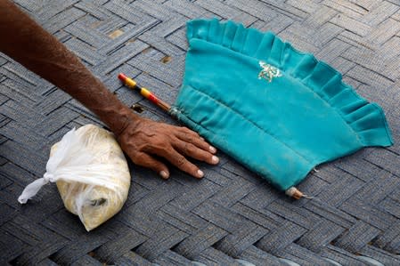 A man sits with a food handout, received from a volunteer, after an earthquake in Jatlan, Mirpur