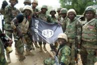 Handout picture from the Nigerian military taken on February 26, 2015 shows troops posing with a flag of Boko Haram after dismantling a Boko Haram camp along Djimitillo Damaturu road, Yobe State in northeastern Nigeria, following fierce fighting