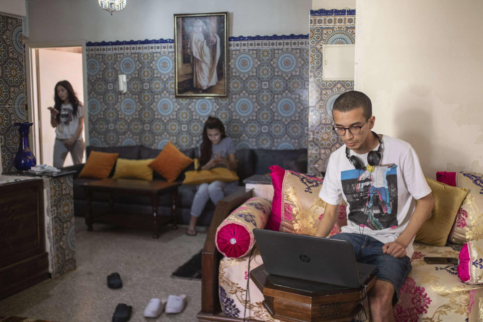 Family members Suhail Lahta, right, Zineb Jammar, center, and Fadila Lahta, left, use their electronic devices as they spend the first day of Eid in lockdown due to the Coronavirus pandemic, in Casablanca, Morocco, Sunday, May 24, 2020. (AP Photo/Mosa'ab Elshamy)