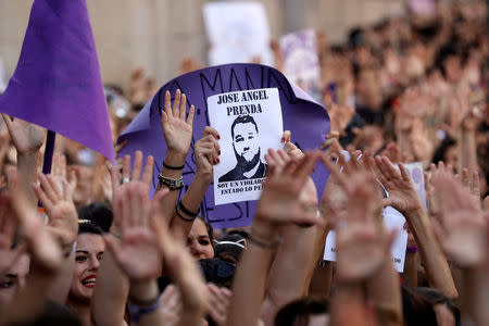 Protesters carry a banner with the image of one the five men known as the "Wolf Pack" cleared of gang rape of a teenager and convicted of a lesser crime of sexual abuse in Madrid, Spain, June 22, 2018. REUTERS/Susana Vera