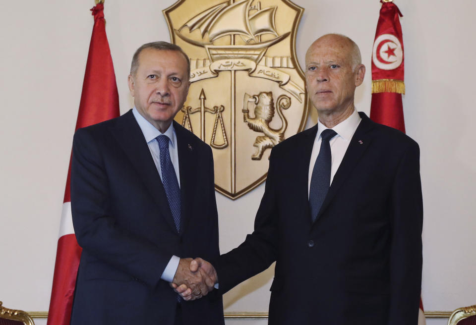 Turkey's President Recep Tayyip Erdogan, left, and Tunisian President Kais Saied shake hands before a meeting, in Tunis, Tunisia, Wednesday, Dec. 25, 2019. Erdogan with top Turkish officials is on an unannounced visit to Tunisia to meet Saied.(Turkish Presidency via AP, Pool)