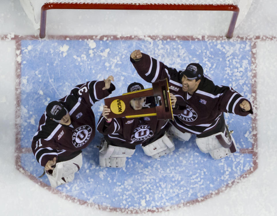 Union's Colin Stevens, center, holds up the championship trophy with teammates Dillon Pieri, left, and Alex Sakellaropoulos, right, following an NCAA men's college hockey Frozen Four tournament game against Minnesota, Saturday, April 12, 2014, in Philadelphia. (AP Photo/Chris Szagola)