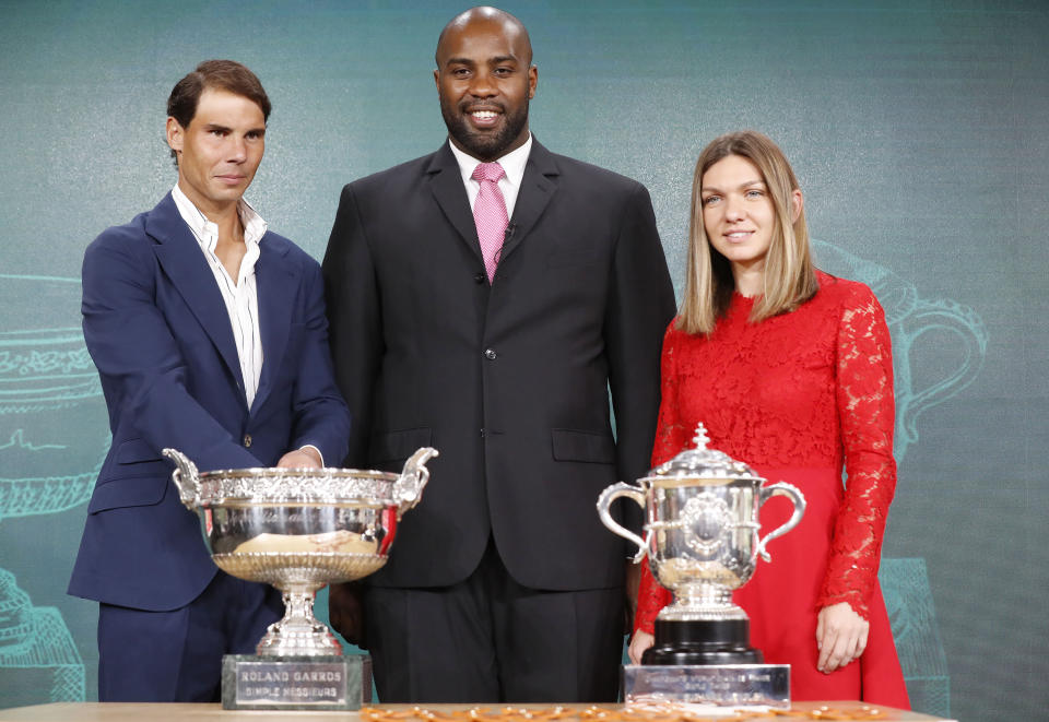 Defending champions Spain's Rafael Nadal, left, French judoka Teddy Riner, center, and Romania's Simona Halep pose next to the cups during the draw of the French Open tennis tournament at the Roland Garros stadium in Paris, Thursday, May 23, 2019. The French Open tennis tournament starts Sunday May 26. (AP Photo/Michel Euler)