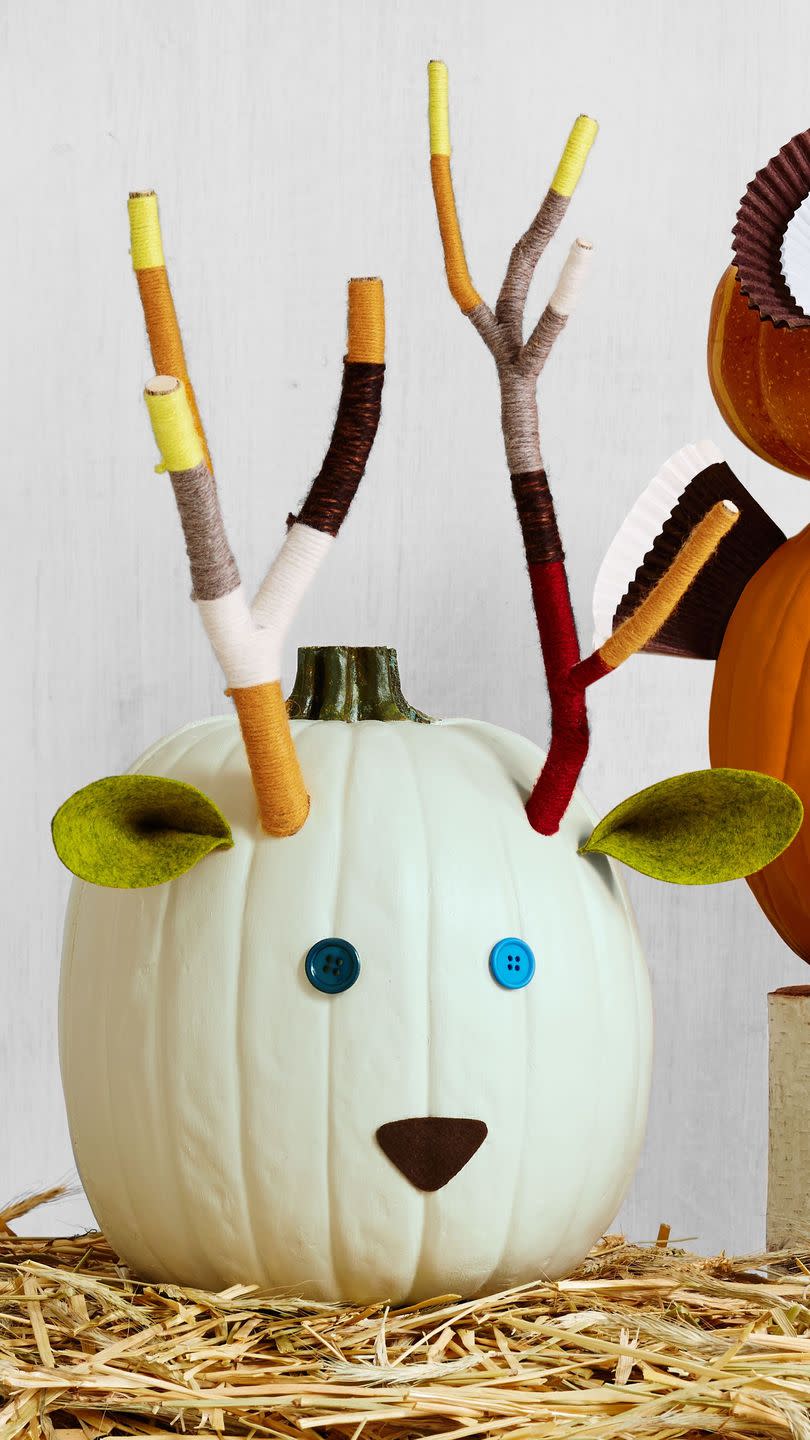 <p>Thanks to yarn-wrapped tree branches, this woodland decoration looks just like the real deal. <strong><br></strong></p><p><strong>Make the pumpkin:</strong> Use a plain white pumpkin (like Lumina) as the base. Assemble tree branches and tightly wrap assorted colors of yarn in color block patterns. Secure loose yarn ends with hot-glue. To attach the antlers, drill two holes into the upper third of the pumpkin, keeping the drill bit angled down so antlers stick up, not out. Attach button eyes, a triangle felt nose, and pinched felt triangle ears with hot-glue. </p>