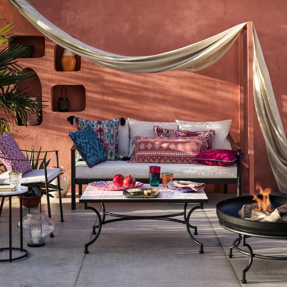 A patio with black metal furniture and Bohemian decor